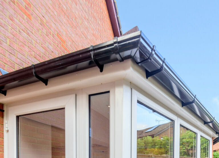Black guttering around a conservatory, by three counties windows