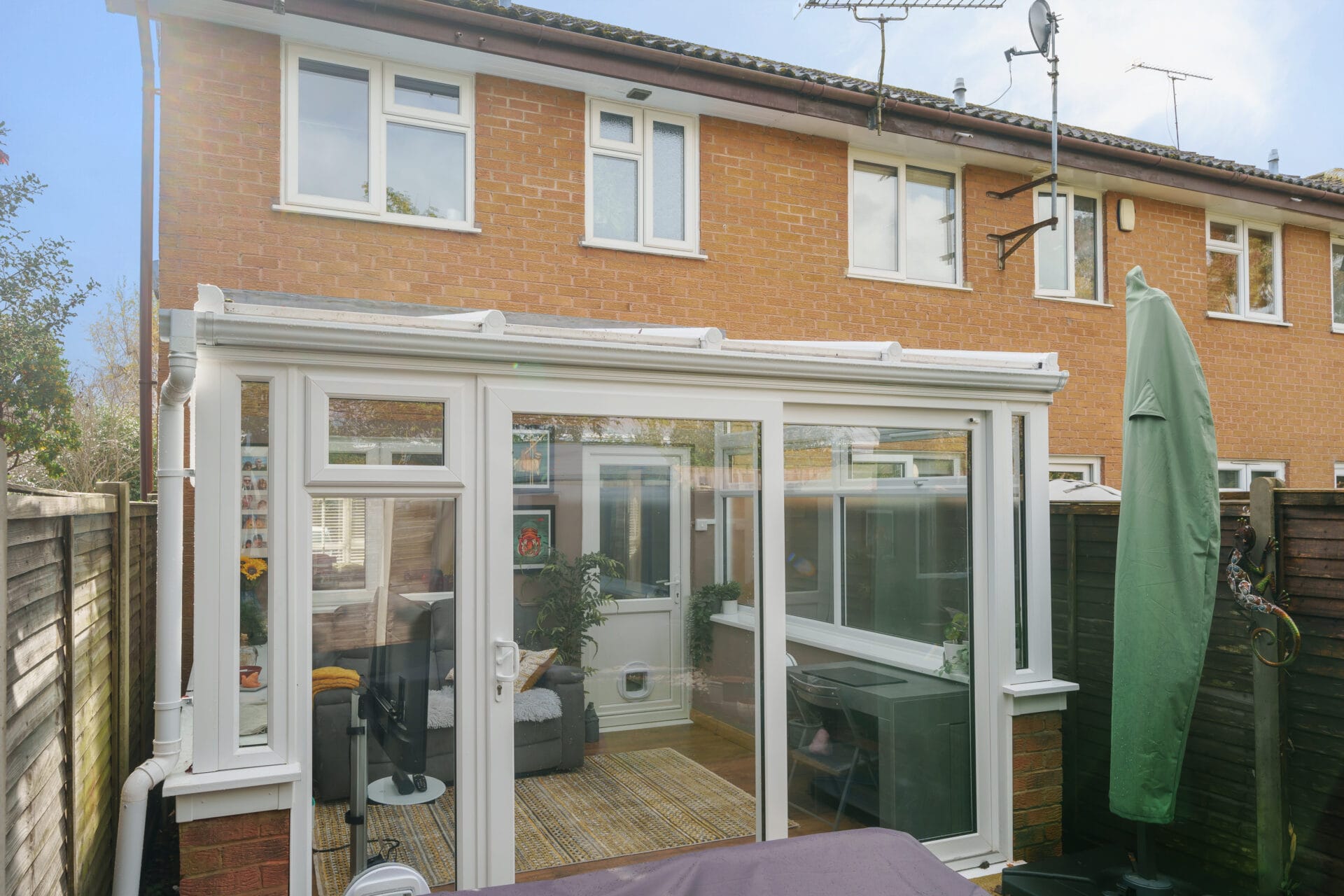 Photo of the back an end-of-terrace house with a Lean-to Conservatory including Ultraframe roof, uPVC patio doors and a cat flap, along with uPVC casement windows